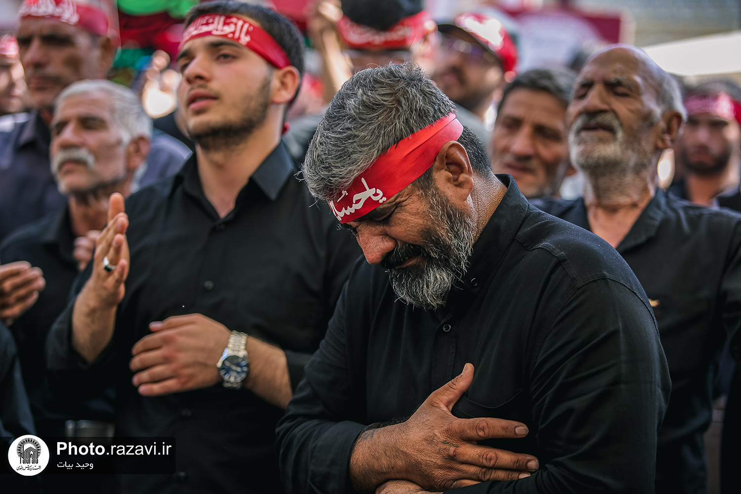 Mourners in dark formal attire with red headbands during the ceremony